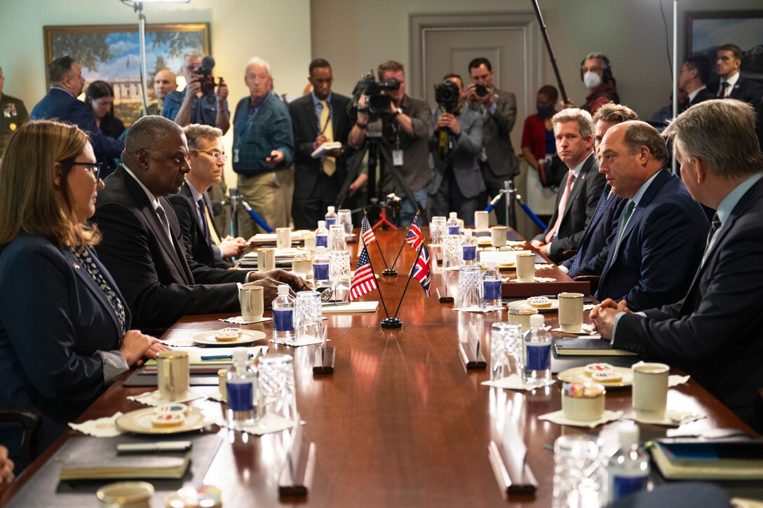 A large group of people meet around a log narrow table.