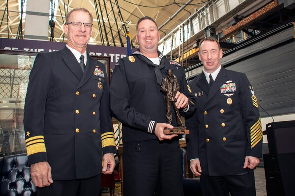 Vice Adm. Yancy B. Lindsey, Commander, Navy Installations Command (CNIC), Commander, and CNIC Force Master Chief Jason Dunn present a trophy to Master-at-Arms 1st Class Brian Allocca, from Hopkinsville, Kentucky, during the FY-21 CNIC Shore Enterprise Sailor of the Year announcement ceremony at the U.S. Navy Museum on board the historic Washington Navy Yard on May 11.