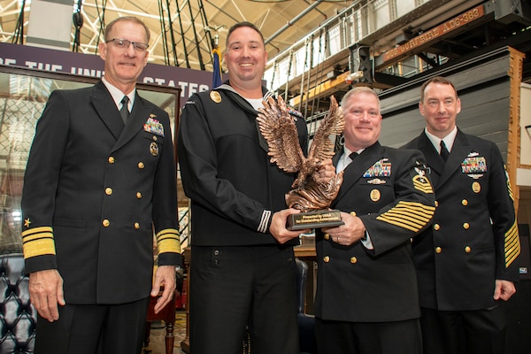 Vice Adm. Yancy B. Lindsey, Commander, Navy Installations Command (CNIC), Commander, Navy Region Japan Command Master Chief Samuel J. Robinson, and CNIC Force Master Chief Jason Dunn present a trophy to Master-at-Arms 1st Class Brian Allocca, from Hopkinsville, Kentucky, during the FY-21 CNIC Shore Enterprise Sailor of the Year announcement ceremony at the U.S. Navy Museum on board the historic Washington Navy Yard on May 11.