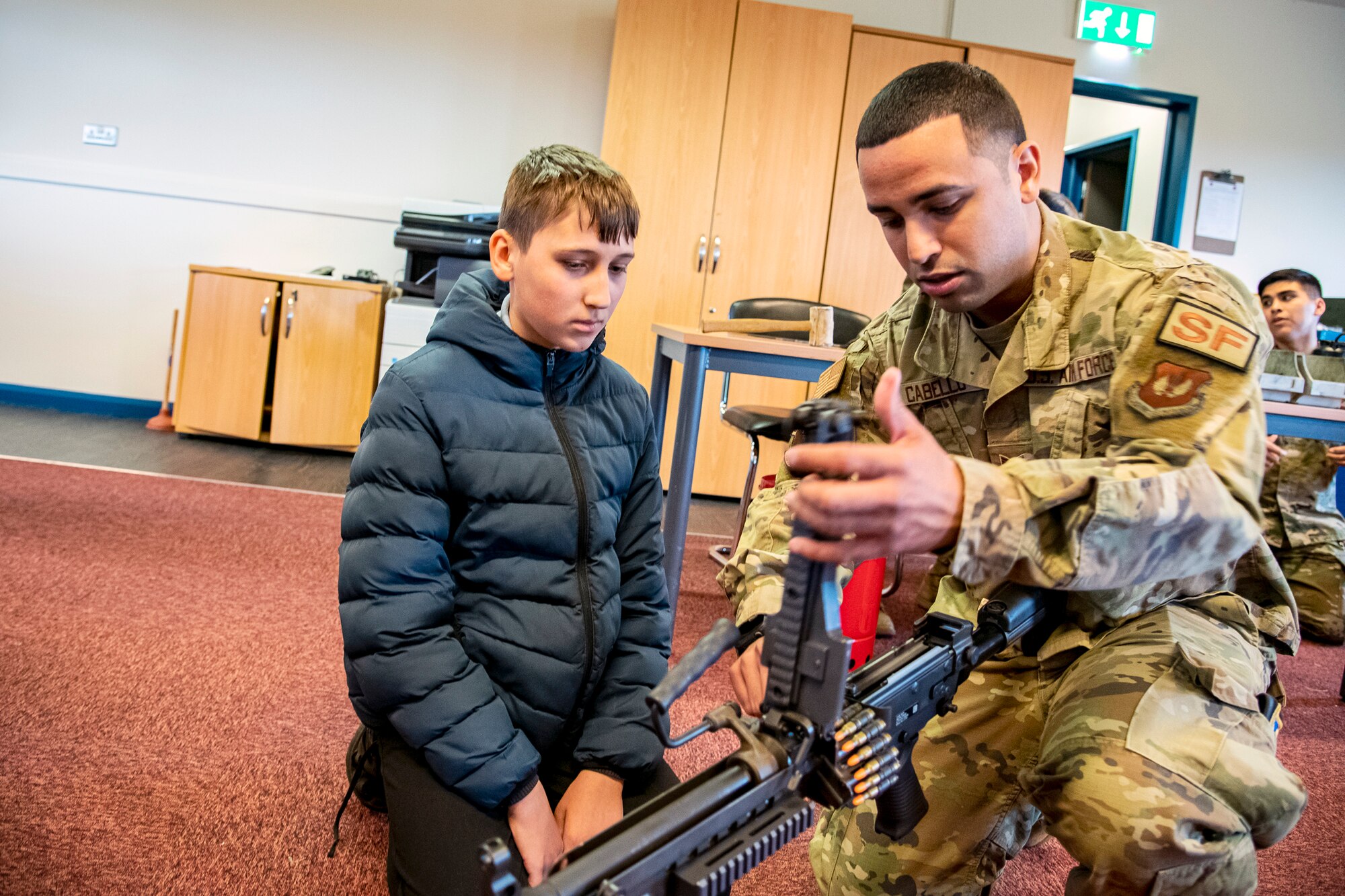 U.S. Air Force Staff Sgt. Jonathon Cabello, 423d Security Forces Squadron combat arms instructor, goes over the components of a M240B machine gun with a local UK student at RAF Molesworth, England, May 10, 2022. The 423d SFS taught students from Huntingdon’s St. Peter’s school about weapons safety and self defense techniques as part of a mentorship program aimed at strengthening the relationship between the 501st Combat Support Wing and local community. (U.S. Air Force photo by Staff Sgt. Eugene Oliver)