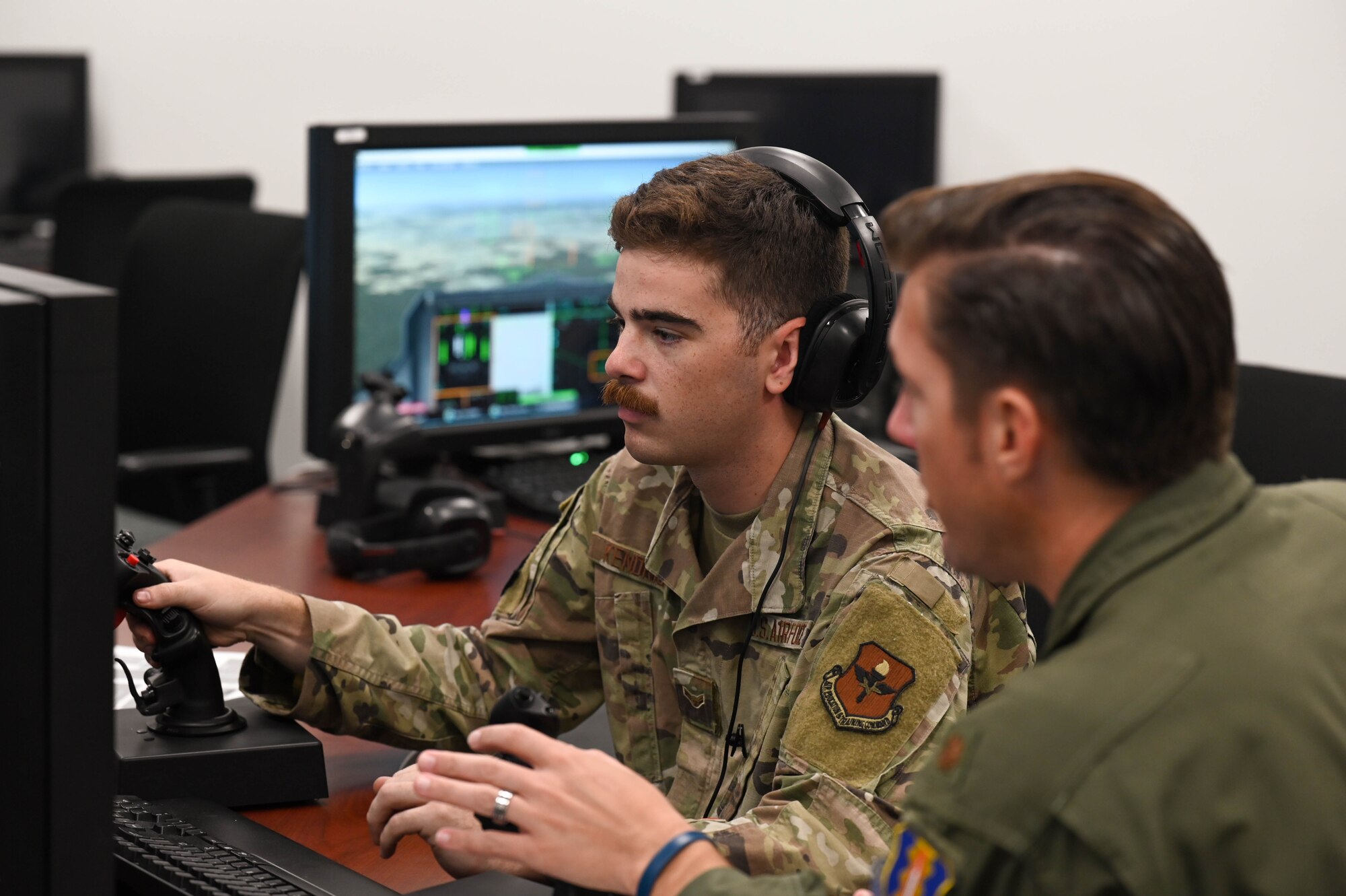 An instructor teaching an airman how to use a simulator during an exercise.