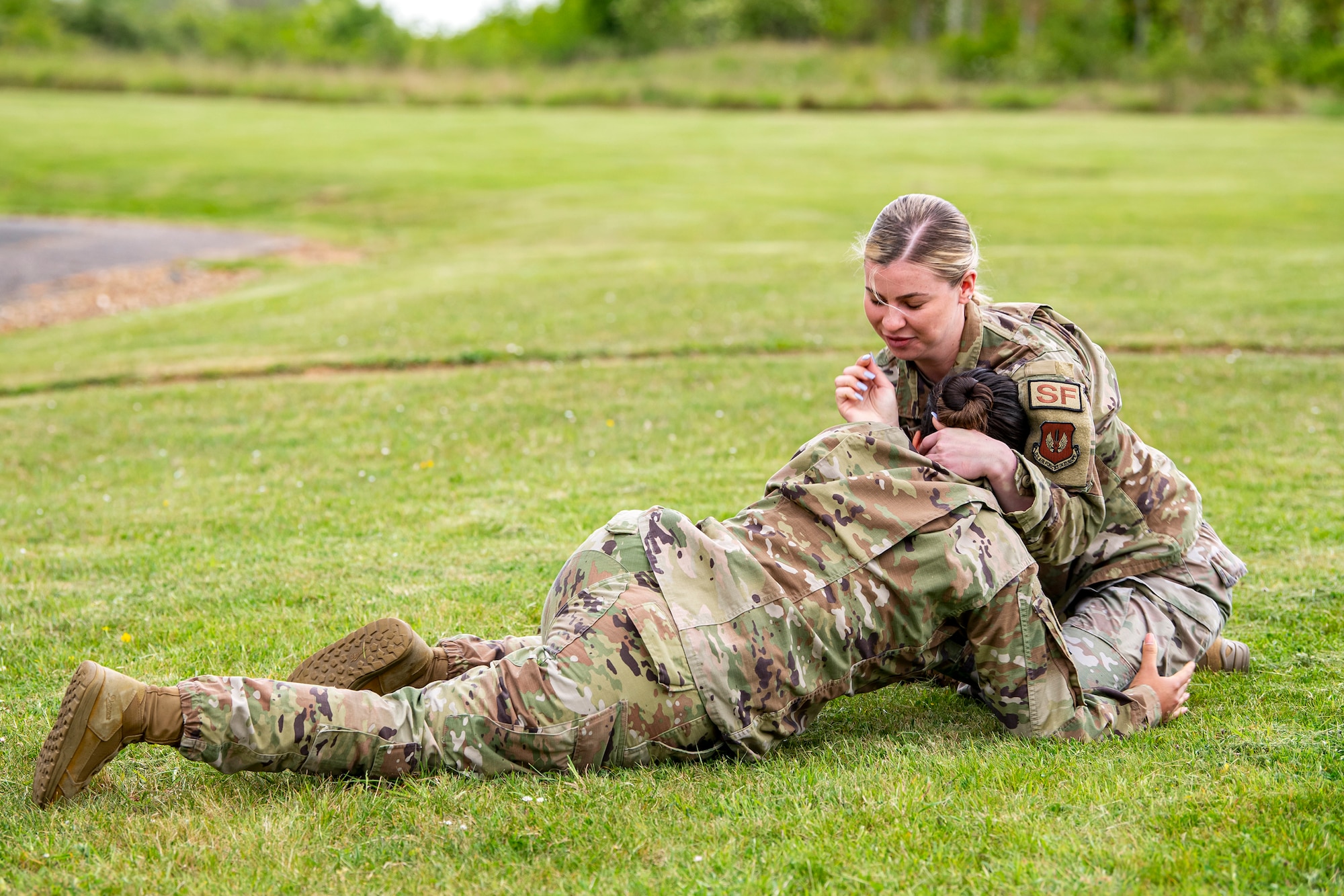 Airman 1st Class Helen Lopez, left, 423d Security Forces Squadron installation patrolman, and Airman 1st Class Sierra Capobianco, base defense operations center controller, demonstrate grappling at RAF Molesworth, England, May 10, 2022. The 423d SFS taught students from Huntingdon’s St. Peter’s school about weapons safety and self defense techniques as part of a mentorship program aimed at strengthening the relationship between the 501st Combat Support Wing and local community. (U.S. Air Force photo by Staff Sgt. Eugene Oliver)