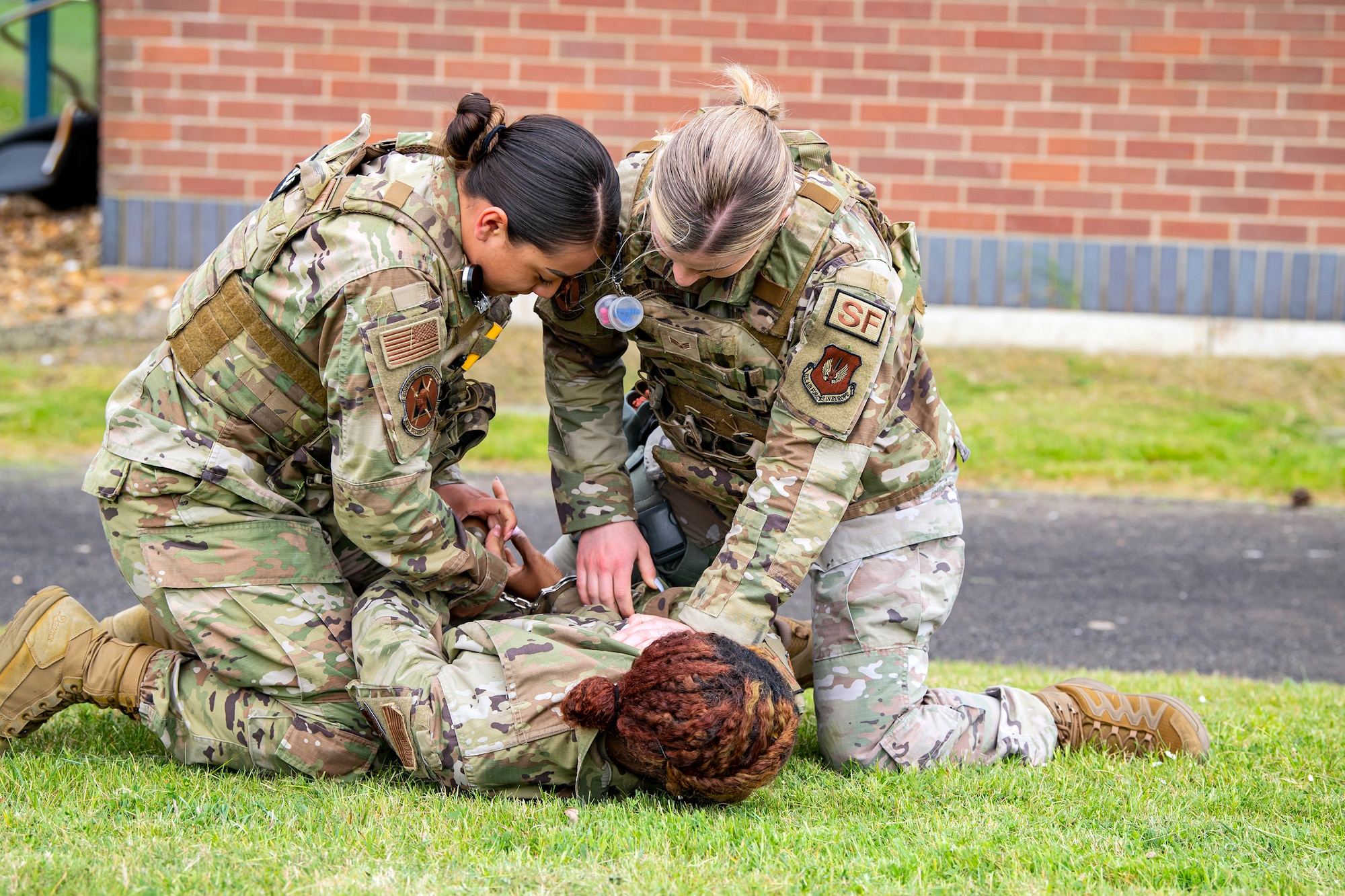 Airman 1st Class Helen Lopez, left, 423d Security Forces Squadron installation patrolman, and Airman 1st Class Sierra Capobianco, base defense operations center controller, demonstrate apprehending a suspect at RAF Molesworth, England, May 10, 2022. The 423d SFS taught students from Huntingdon’s St. Peter’s school about weapons safety and self defense techniques as part of a mentorship program aimed at strengthening the relationship between the 501st Combat Support Wing and local community. (U.S. Air Force photo by Staff Sgt. Eugene Oliver)