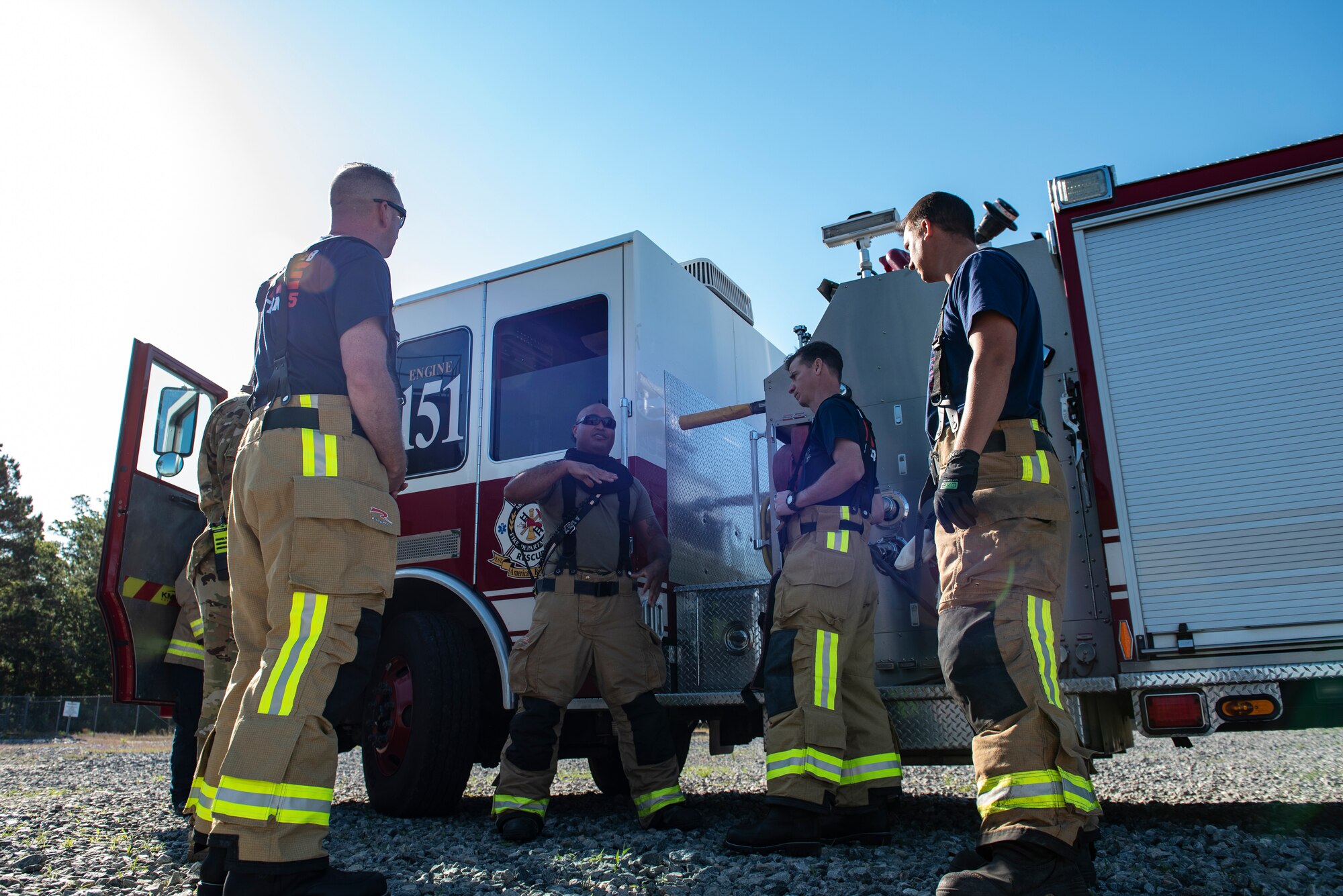 A photo of five men standing next to a fire truck.