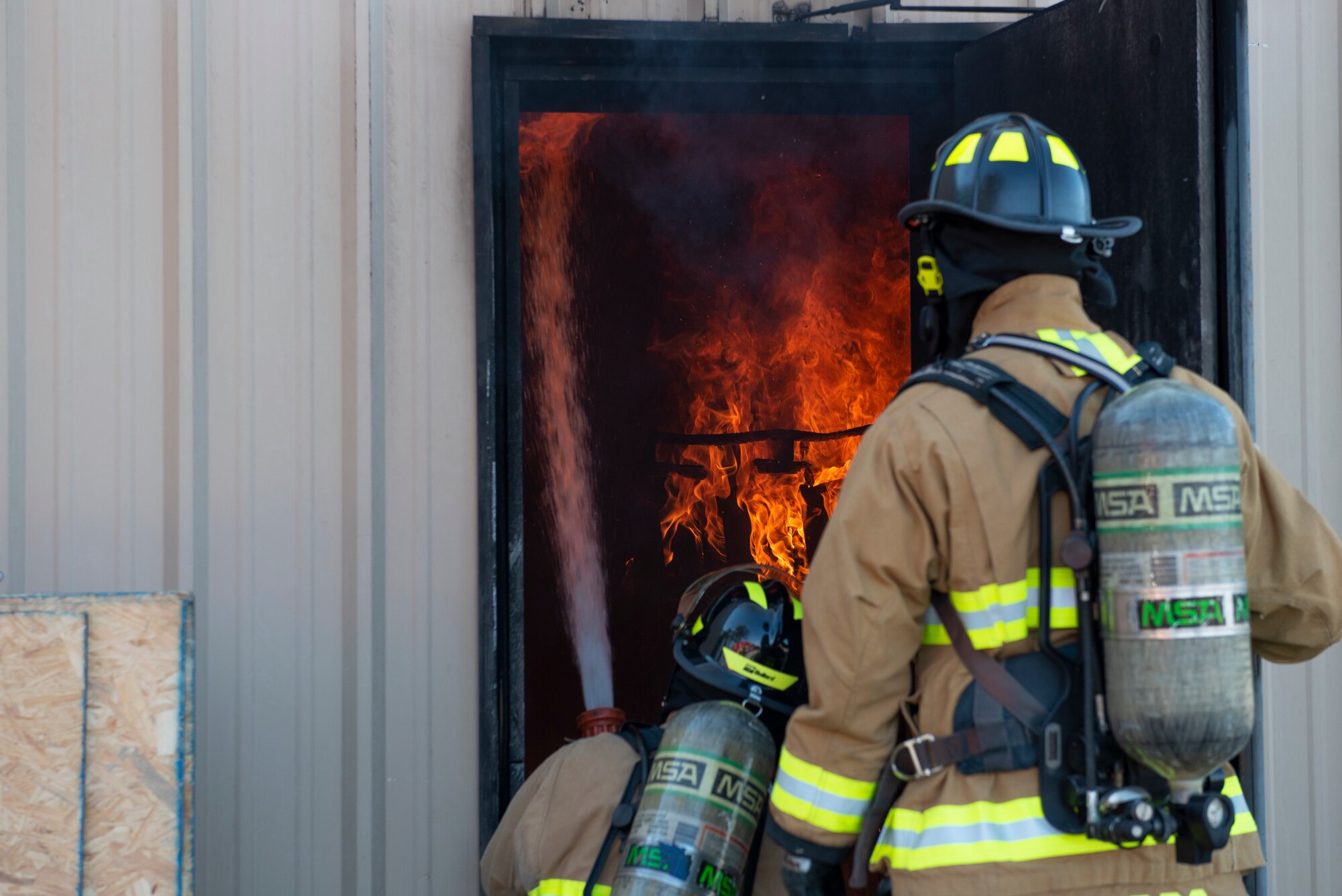 A photo of two fire fighters putting out a fire.