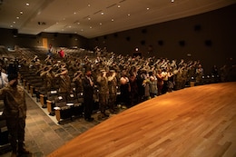 Soldiers and civilians stand for the National Anthem