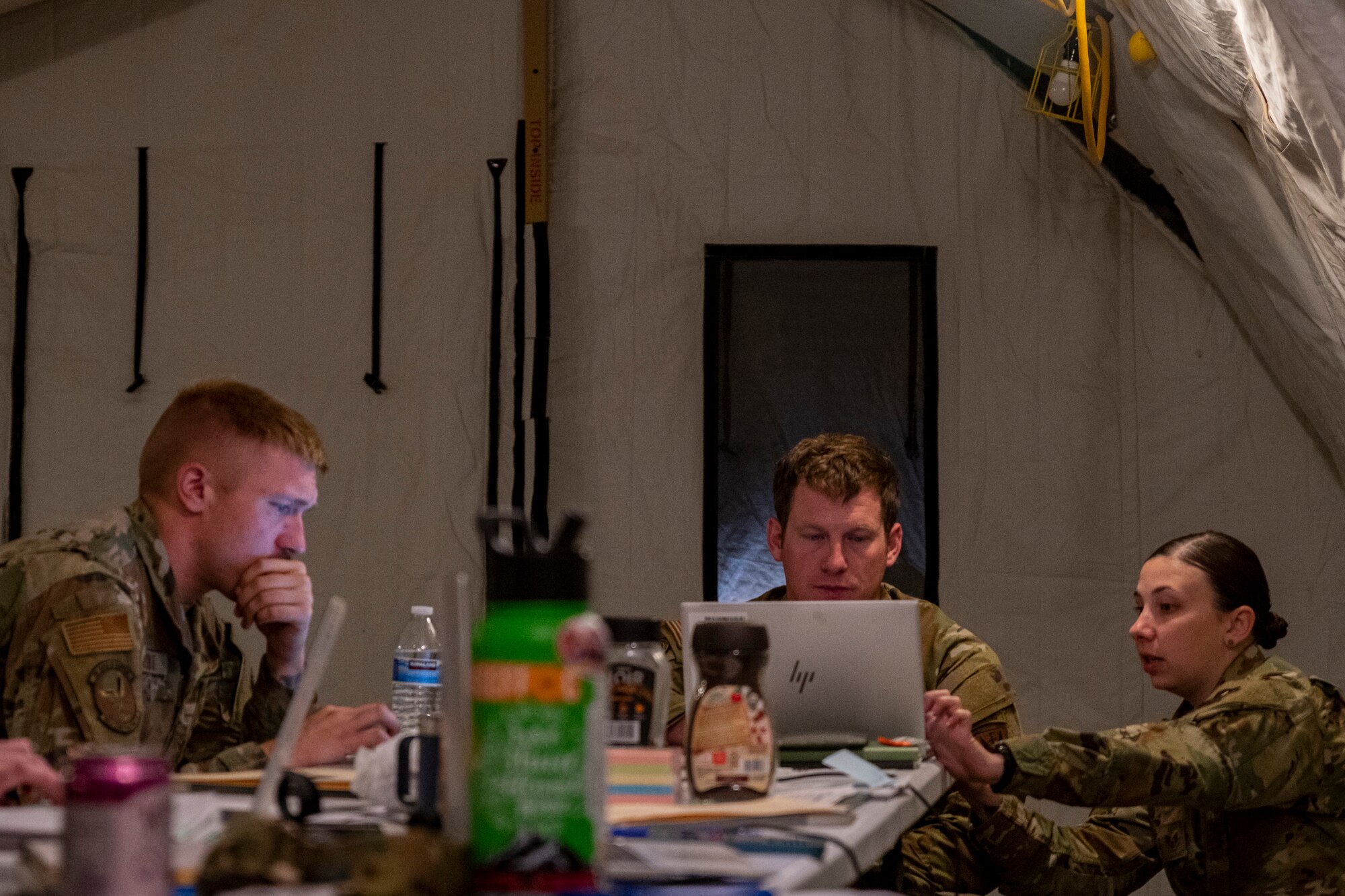 A photo of a group of people working at a table setup inside a tent.