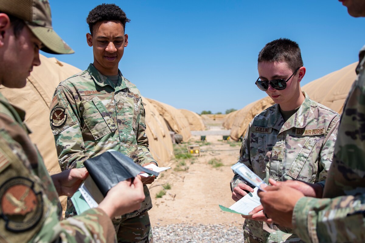 A photo of a group of Airmen pretend to exchange funds during a simulated transaction.