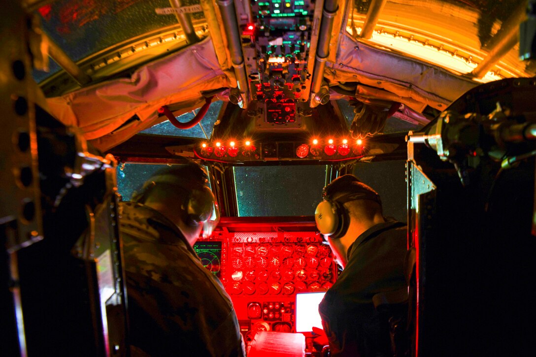 Two airmen sit in the cockpit of an aircraft.