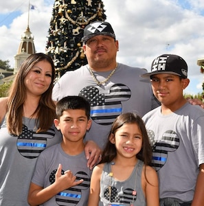 Man and woman standing with their 3 children, two boys and one girl.