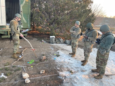 Soldiers stand around a sand map.