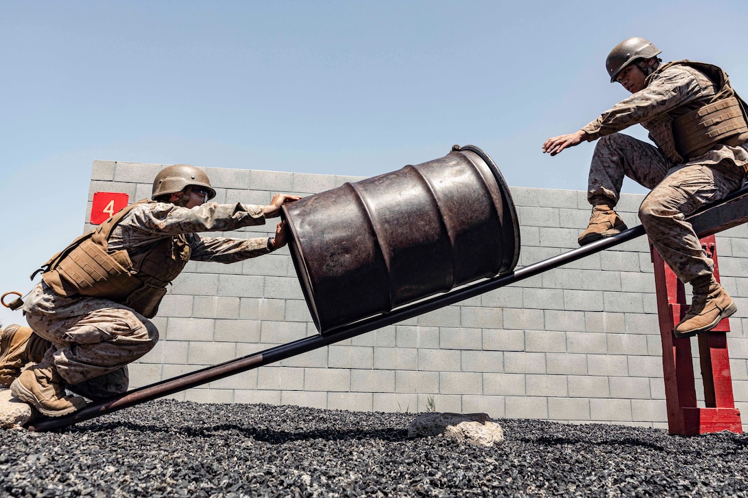 Marine Corps officer candidates pass a down a metal slide.