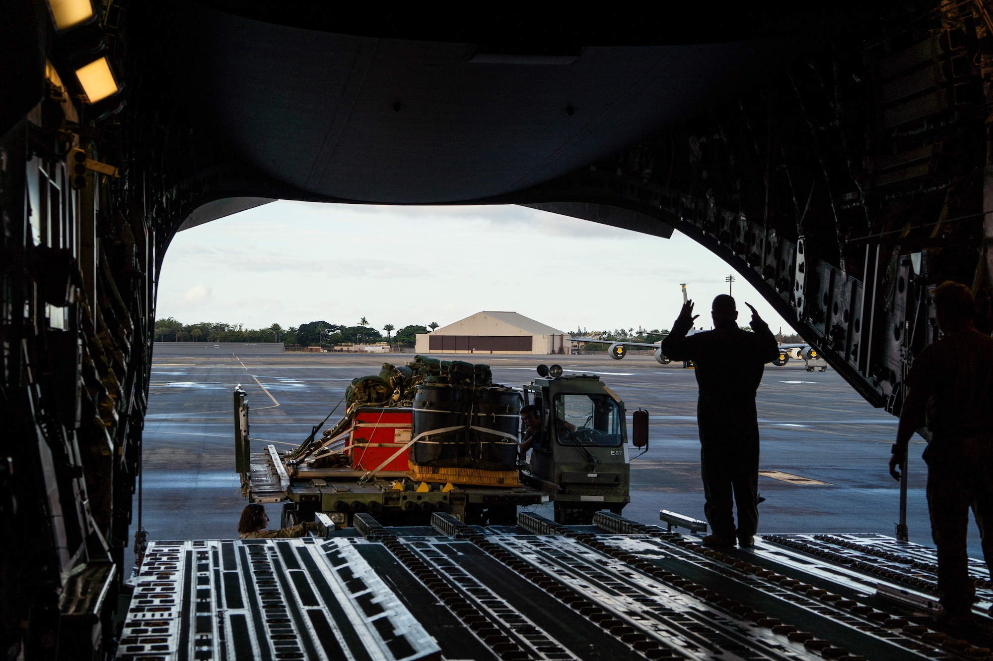 U.S. Air Force Master Sgt. Randall Yamada, 204 Airlift Squadron loadmaster, marshals a Tunner 60K Loader to the ramp of a C-17 Globemaster III before takeoff during Exercise Global Dexterity 2022 at Joint Base Pearl Harbor-Hickam, Hawaii, May 4, 2022. The Royal Australian Air Force visited JBPHH to join both active duty and National Guard C-17s for training missions around the Hawaiian Islands to develop tactical airlift and airdrop capabilities. (U.S. Air Force photo by Airman 1st Class Makensie Cooper)