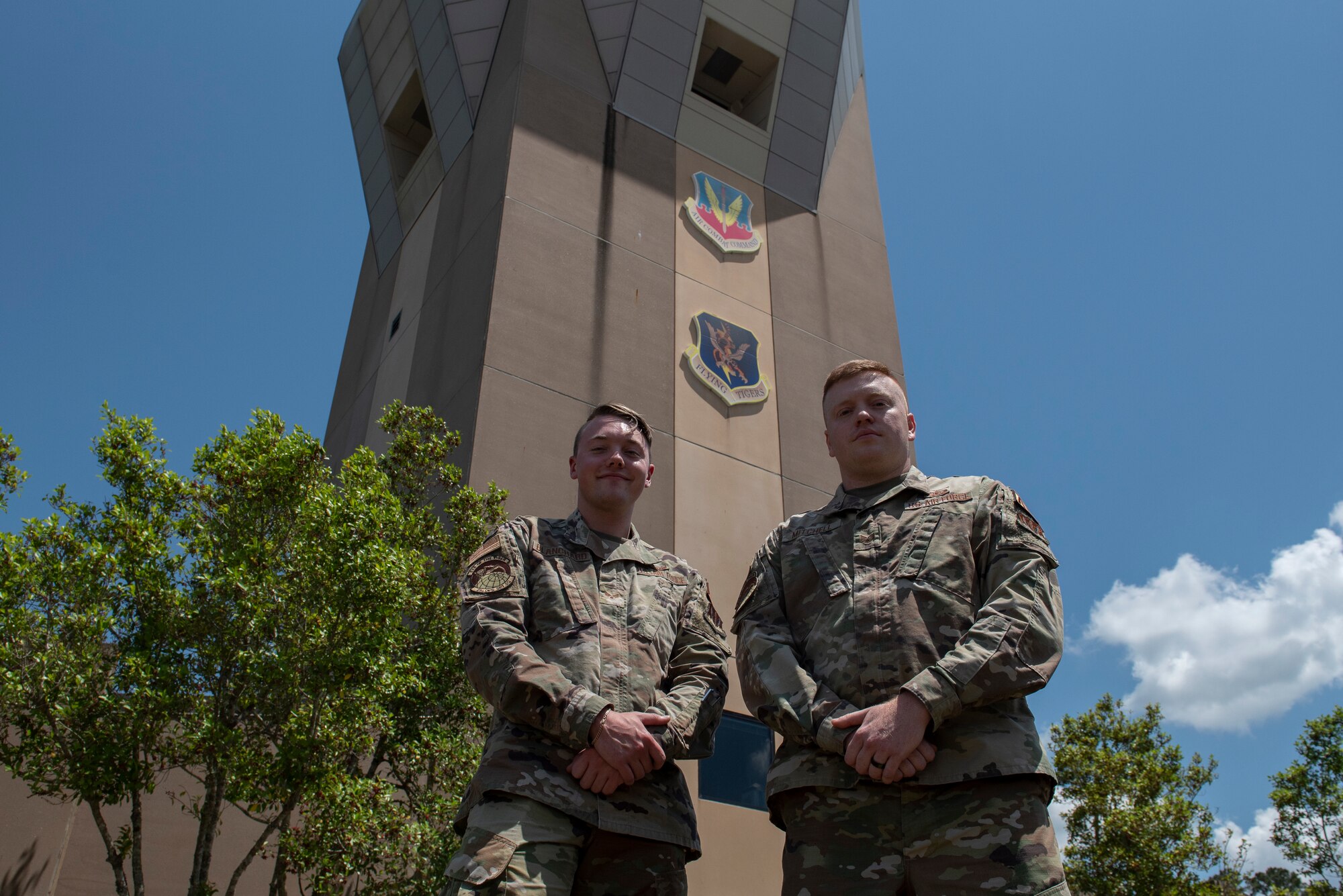 A photo of two airmen standing in front of a control tower.