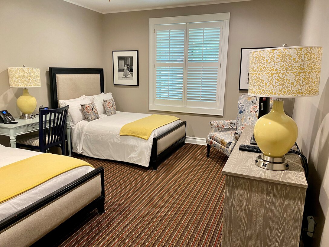 Two beds, a chair, dresser and desk are in a room.