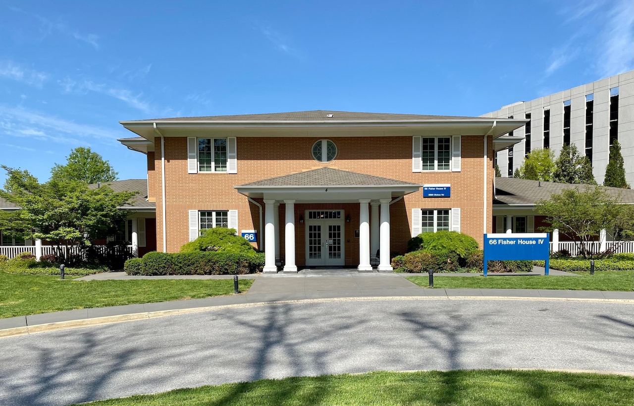 A large porch with columns frames the entrance to a brick building. A sign bears the words Fisher House.