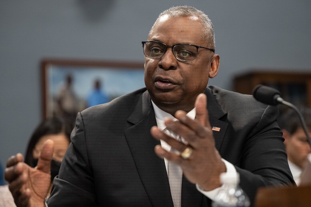 Secretary of Defense Lloyd J. Austin III gesticulates while speaking at a table.