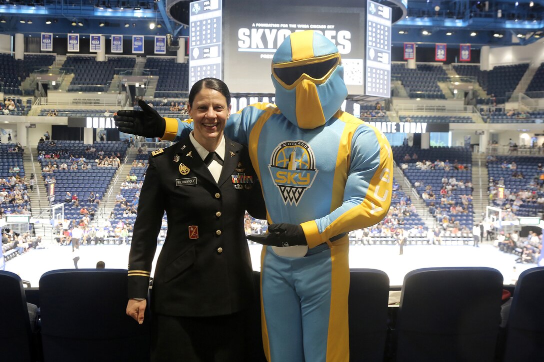 U.S. Army Reserve Maj. Jodi Wernikoff, left, headquarters and headquarters company commander of the 85th U.S. Army Reserve Support Command, pauses for a photo with Sky Guy, the Women’s National Basketball Association’s Chicago Sky team mascot, at the Chicago Sky’s home game versus the New York Liberty, May 12, 2022.