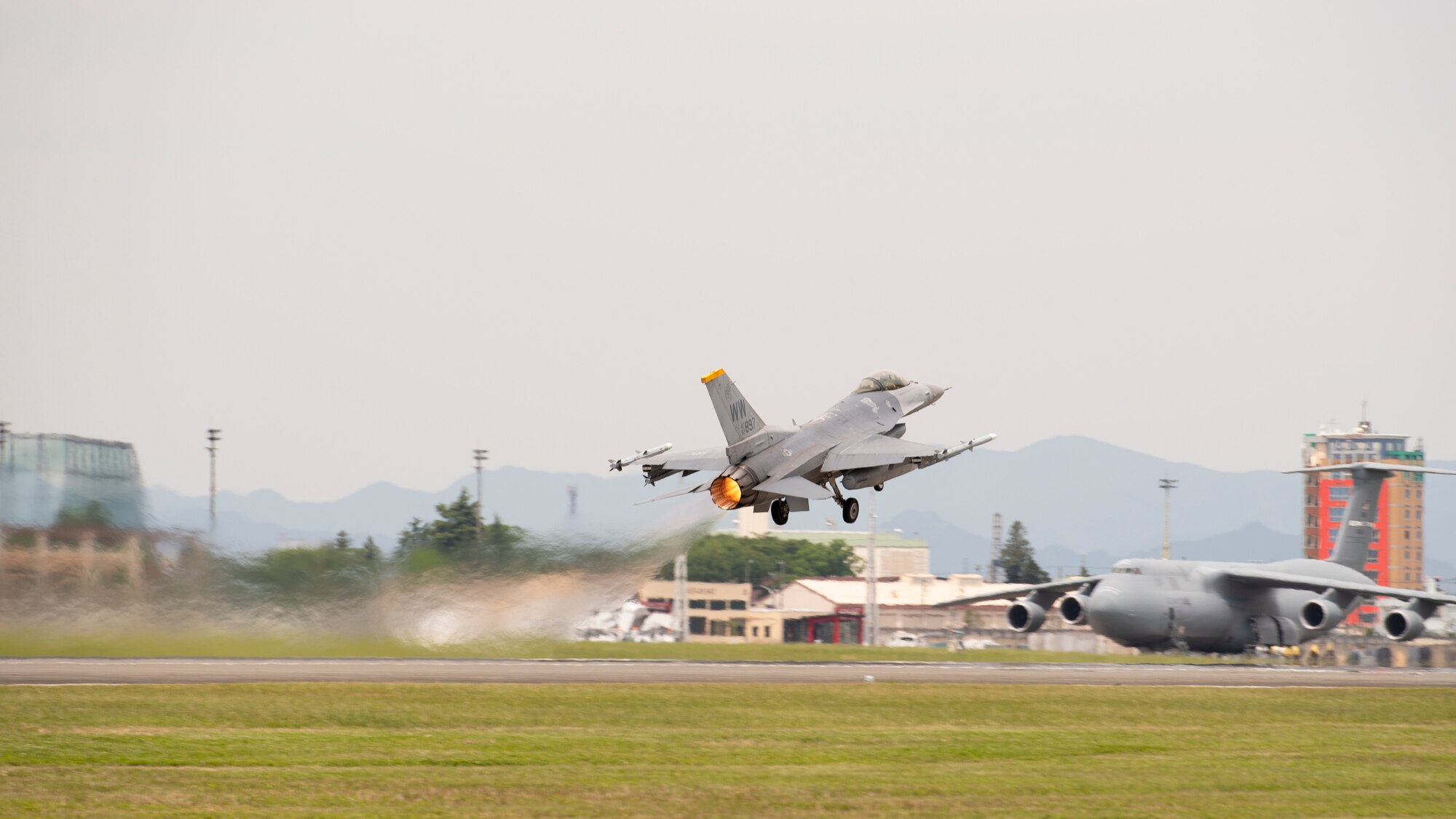 A view from behind and below of a fighter jet taking off from the runway.