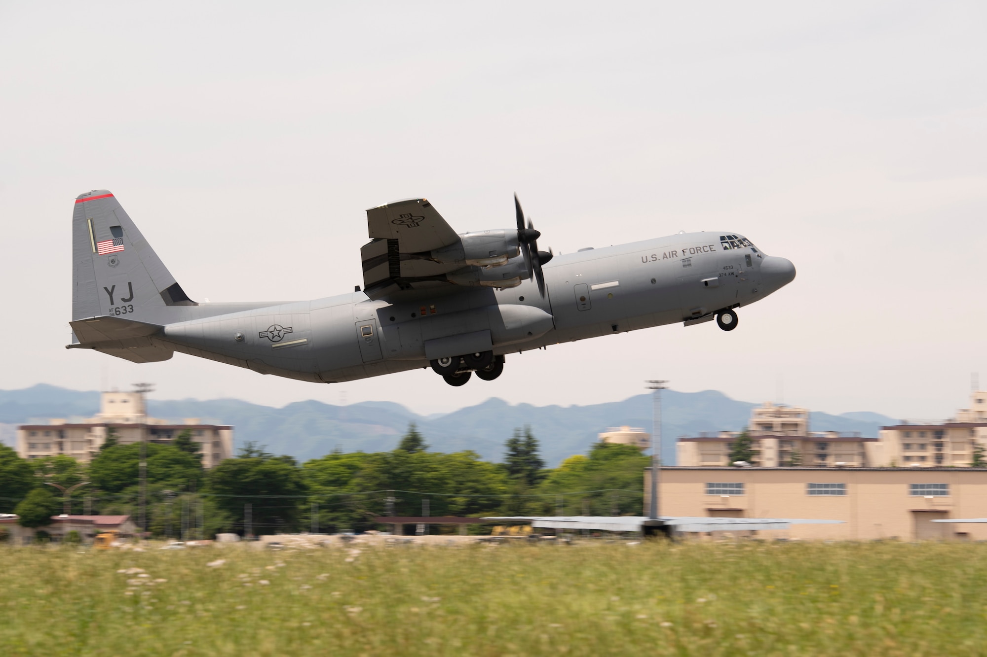 A sideways closeup view of a large prop cargo aircraft lifting off the runway during takeoff.