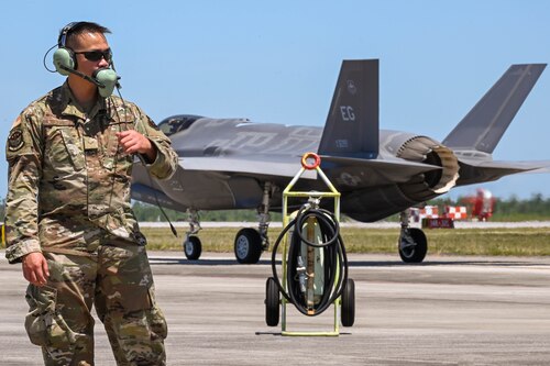 Crew Chief of the flightline with ear pro  standing in front of an F-35A Lightning II.