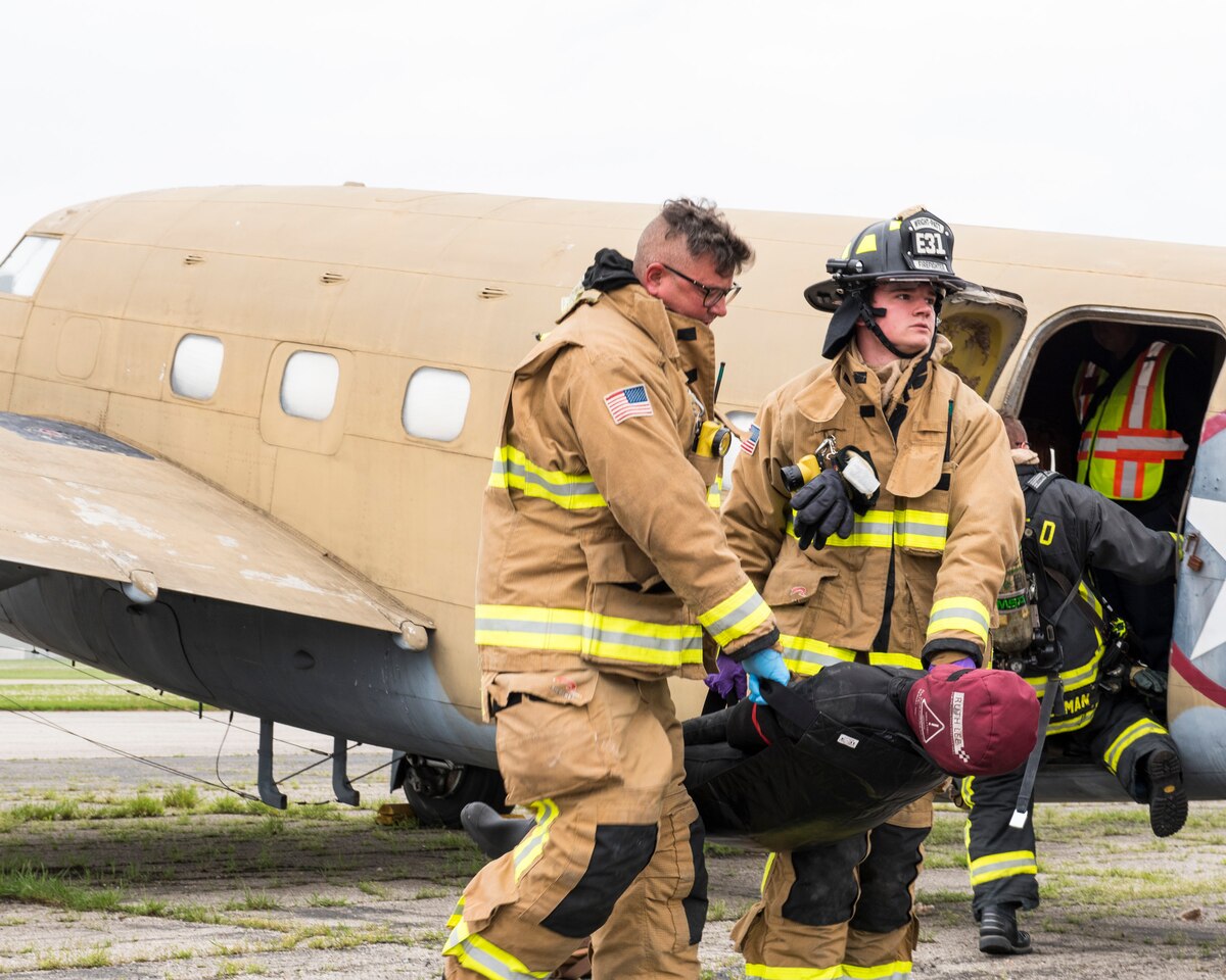 Firefighters from the 788th Civil Engineer Squadron carry a dummy victim to safety, May5, 2022, during a mass casualty exercise at Wright-Patterson Air Force Base, Ohio.
