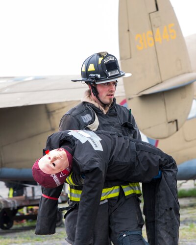 A firefighter from the 788th Civil Engineer Squadron carries a dummy victim to safety, May 5, 2022, during a mass casualty exercise at Wright-Patterson Air Force Base, Ohio.
