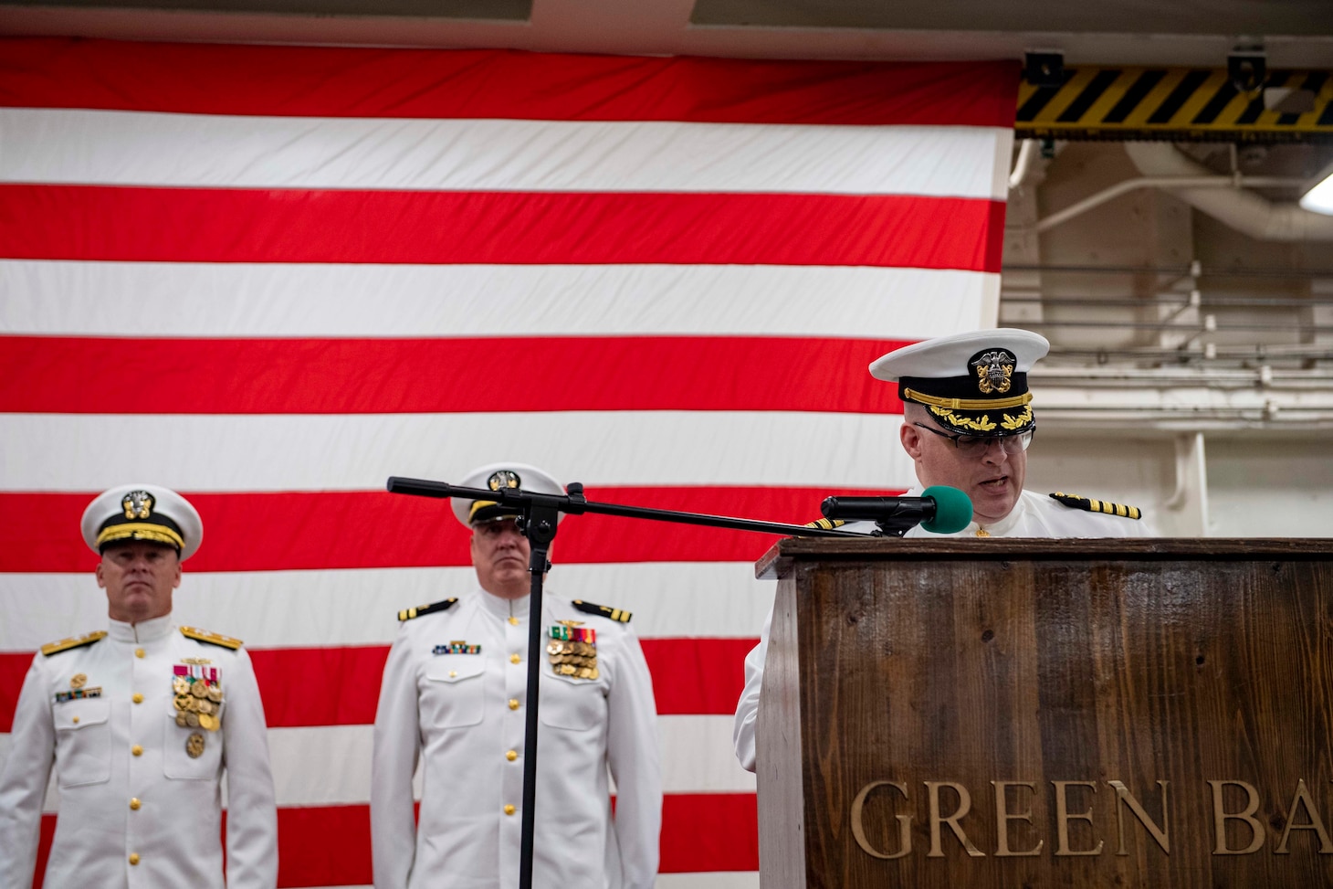 SASEBO, Japan (May 12, 2022) Capt. James T. Robinson, commanding officer of the forward-deployed amphibious transport dock ship USS Green Bay (LPD 20), reads his orders during his change-of-command ceremony in the ship’s vehicle stowage area. Green Bay, part of Amphibious Squadron 11, is operating in the U.S. 7th Fleet area of responsibility to enhance interoperability with allies and partners, and serve as a ready response force to defend peace and stability in the Indo-Pacific region. (U.S. Navy photo by Mass Communication Specialist Seaman Matthew Bakerian)