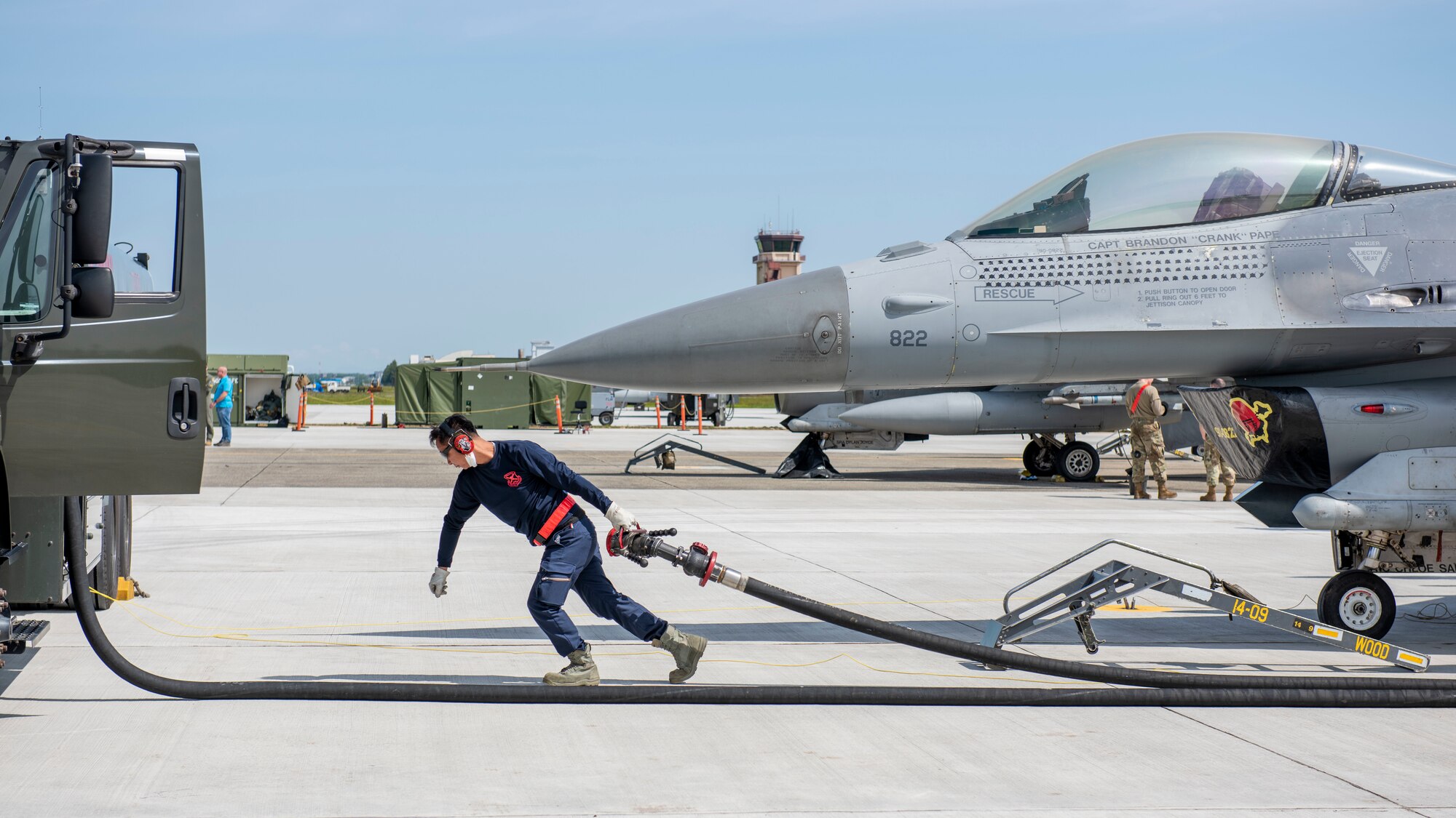 An operator pulls a fuel hose towards a refueling truck