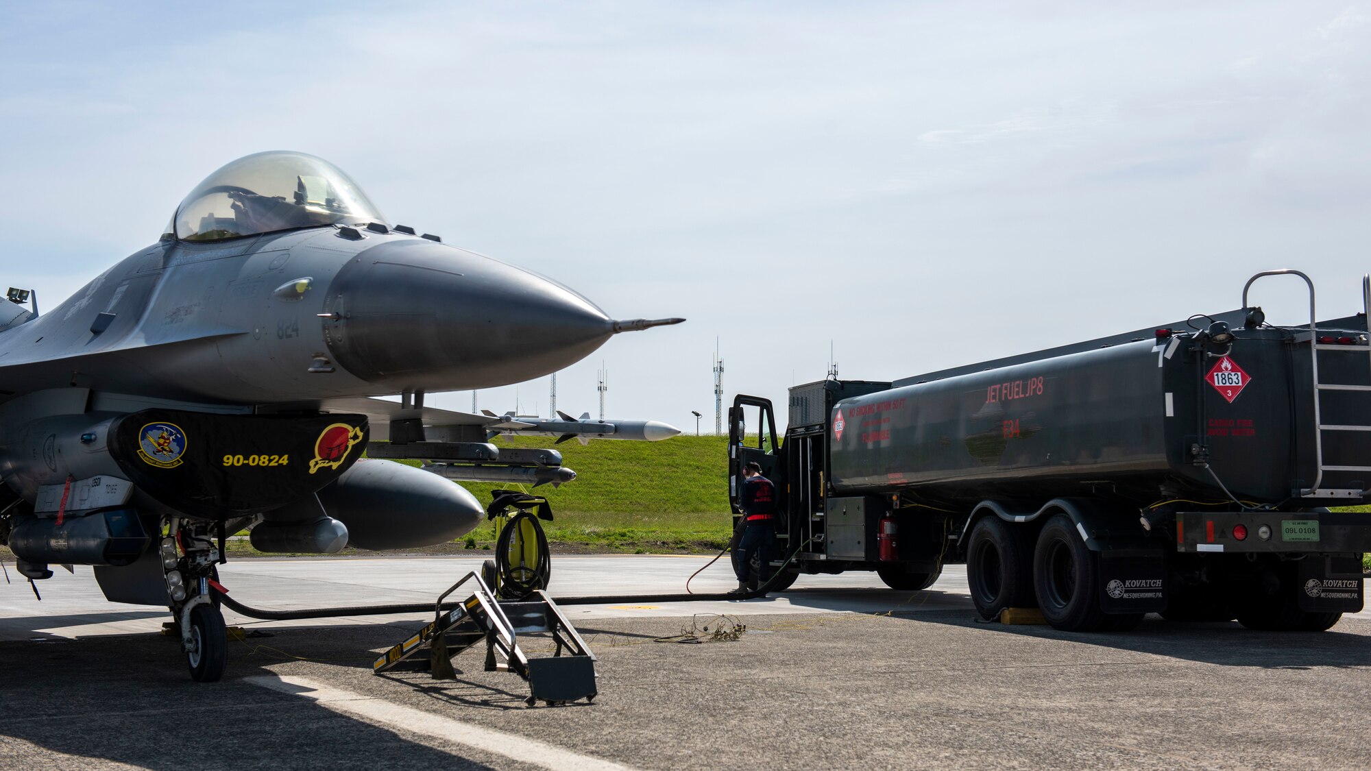 A refueling truck dispenses fuel to an F-16 Fighting Falcon jet