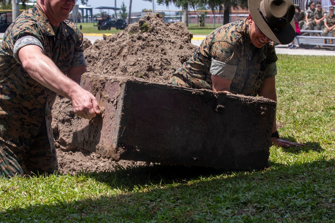 Maj. Matthew A. Lamb, Executive Officer of the 4th Recruit Training Battalion, and Sgt. Maj. Sigrid Rivera, Battalion Sergeant Major of the 4th Recruit Training Battalion, remove the time capsule from the ground on Marine Corps Recruit Depot Parris Island S.C., May 5, 2022. The time capsule contained relics from various decades of women’s service in the Marine Corps.