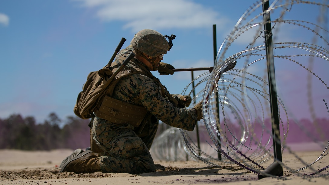 A U.S. Marine with 2d Combat Engineer Battalion, 2d Marine Division, cuts through concertina wire during the Sapper Leaders Course on Camp Lejeune, North Carolina, May 11, 2022. The Sapper Leaders Course provides combat engineer squad leaders with the technical and tactical proficiency required to provide mobility, counter mobility and survivability to infantry company commanders.