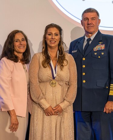 Abbigail McCracken (middle),the winner of the Armed Forces Insurance Military Spouse of the Year for the Coast Guard, stands with the Commandant of the Coast Guard Adm. Karl Schultz (right) and his wife Dawn (left), shortly after being presented with the Coast Guard of the Year medallion, May 5, 2022.