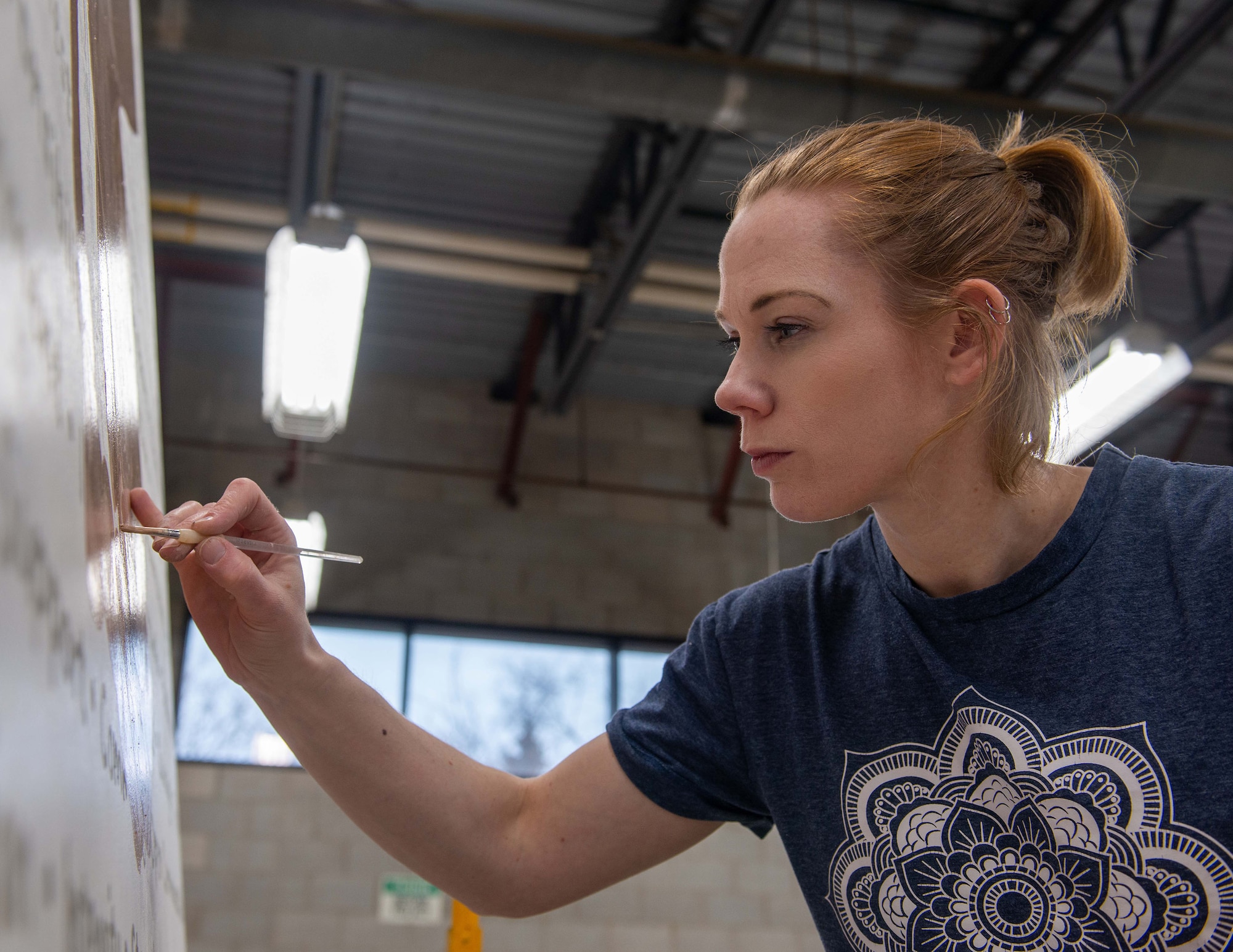 Elizabeth Swanson, the 934th Airlift Wing Sexual Assault Response Coordinator, paints a mural at the Minneapolis-Saint Paul Air Reserve Station, March 24, 2022. Swanson has been working on the mural since January this year in preparation for Sexual Assault Awareness Month. (U.S. Air Force photo by Staff Sgt. Timothy Leddick, Jr.)