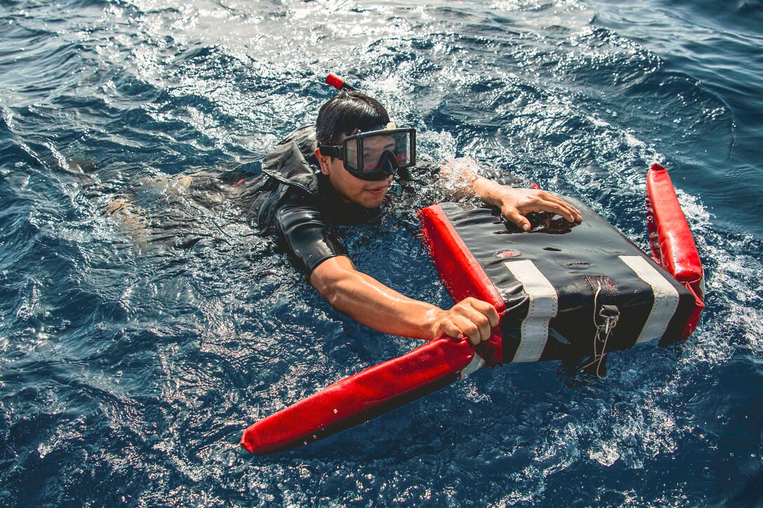 A sailors simulates a rescue in a body of water.