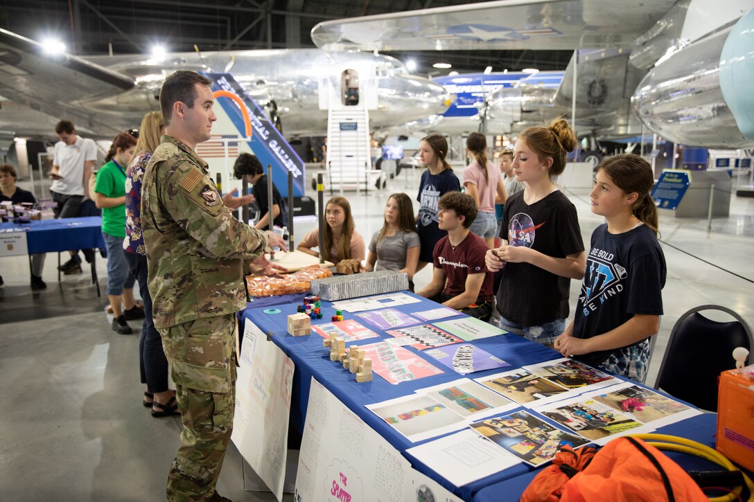 WRIGHT-PATTERSON AIR FORCE BASE (AFRL), Ohio – First Lt. Kyle Bucklew, left, warfighter training program manager, 711th Human Performance Wing, part of Air Force Research Laboratory, interacts with students discussing their projects during the Full Throttle STEM event May 12, 2022, at the National Museum of the United States Air Force, at Wright-Patterson Air Force Base, Ohio. This was the first time the science, technology, engineering and math event extended to the museum. The Air Force Research Laboratory’s Gaming Research Integration for Learning Lab, or GRILL, hosted the events with 12 schools in attendance between both locations. (U.S. Air Force photo / Will Graver)