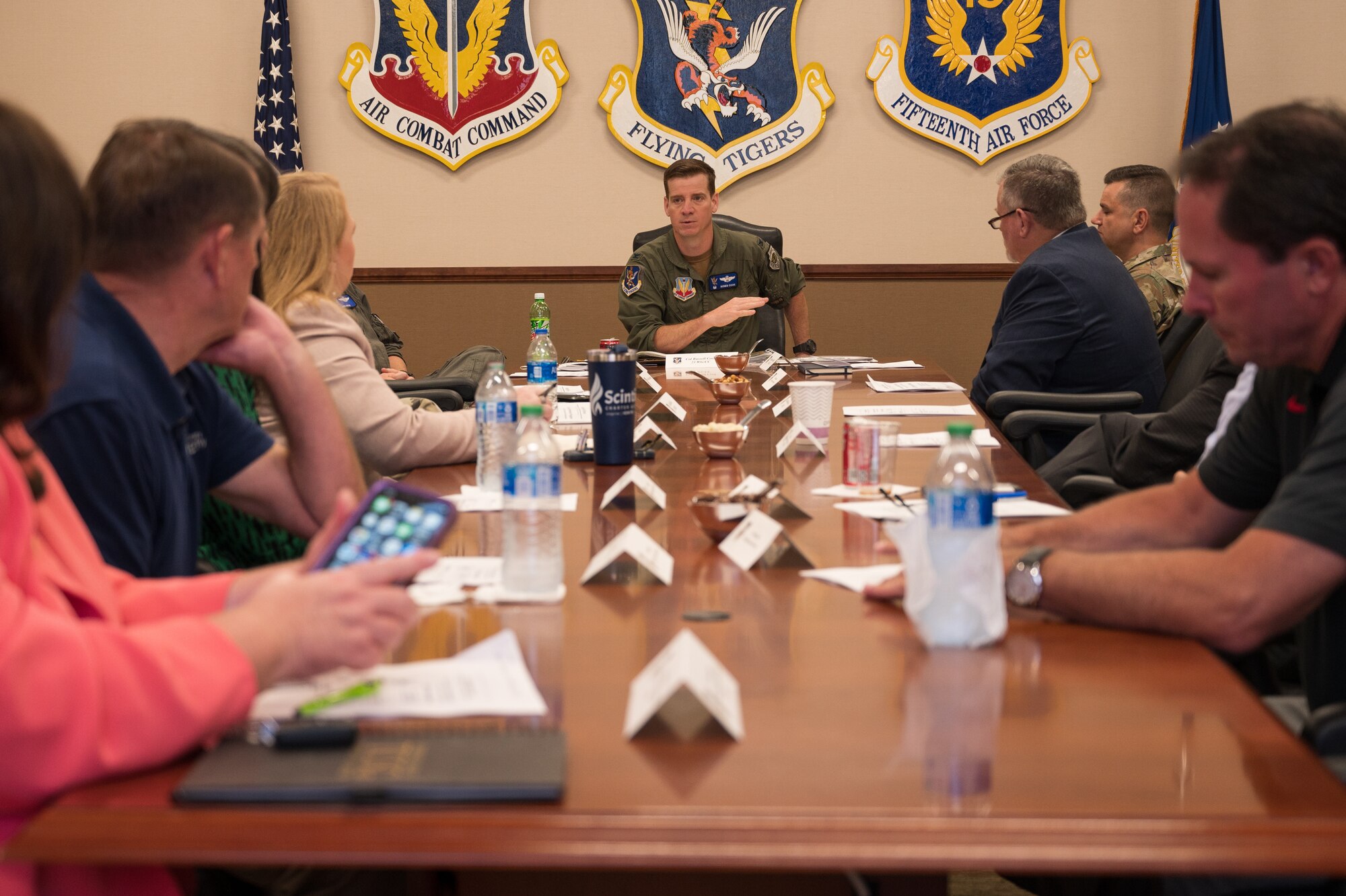 A photo of a group of people sitting at a table and listening to a meeting.