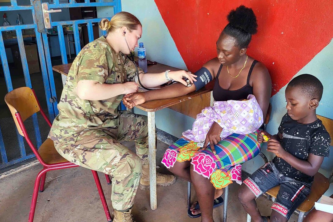 A soldier takes a woman's blood pressure.