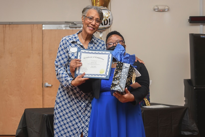 Adreinne Barnett, Project SEARCH business liaison for Joint Base Andrews, presents a graduation certificate to De’Nisha Mayo, Project SEARCH intern, at the graduation of the Project SEARCH class of 2022 at JBA, Md., May 13, 2022. Project SEARCH, which began in 1996 at Cincinnati Children's Hospital Medical Center, establishes internships at local businesses and government organizations for students with intellectual and developmental disabilities. (U.S. Air Force photo by Senior Airman Spencer Slocum)