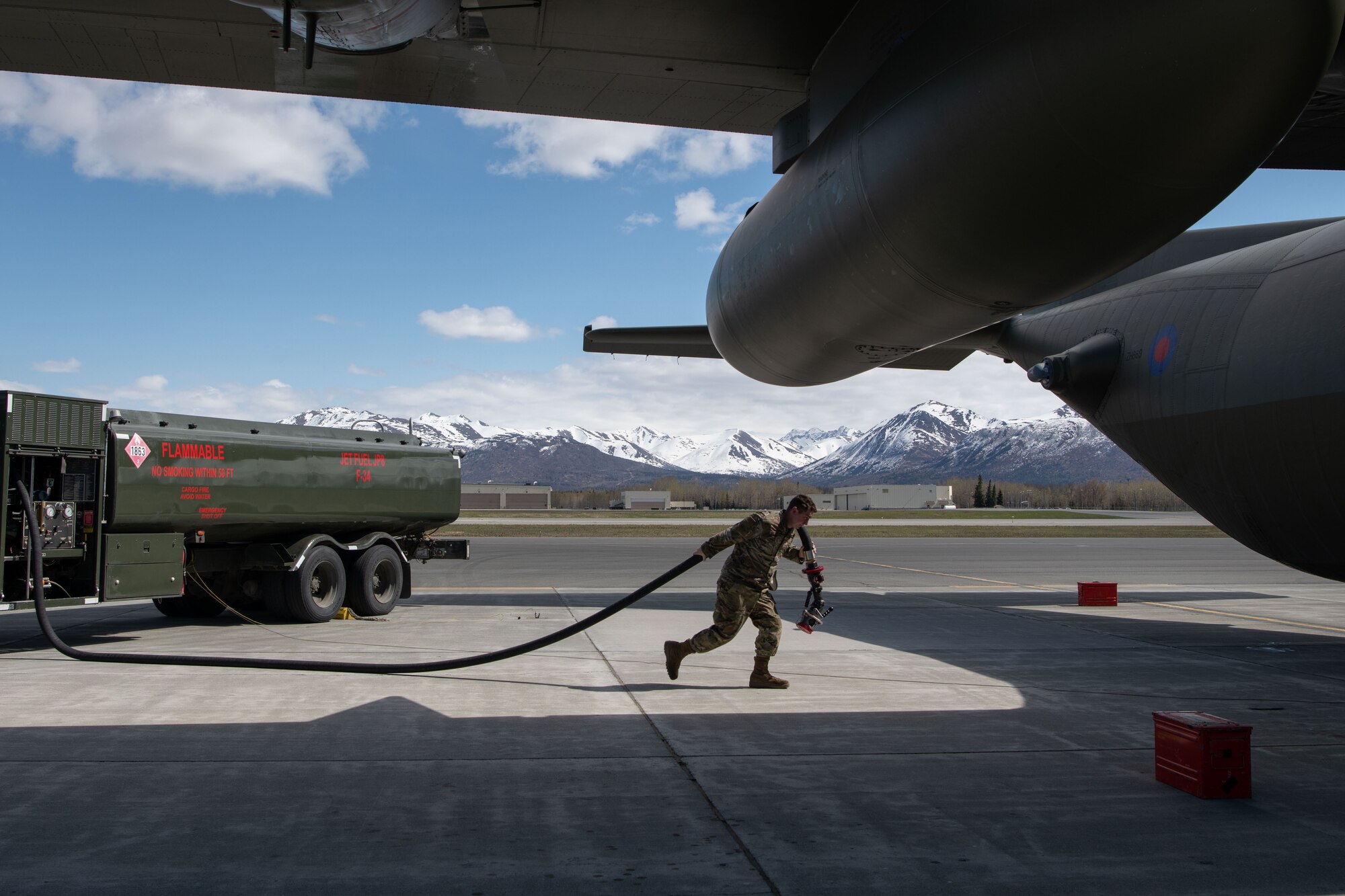 A photo of a man dragging a hose to a plane