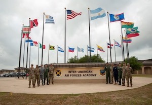Instructors stand outside IAAFA headquarters with flags flying in background