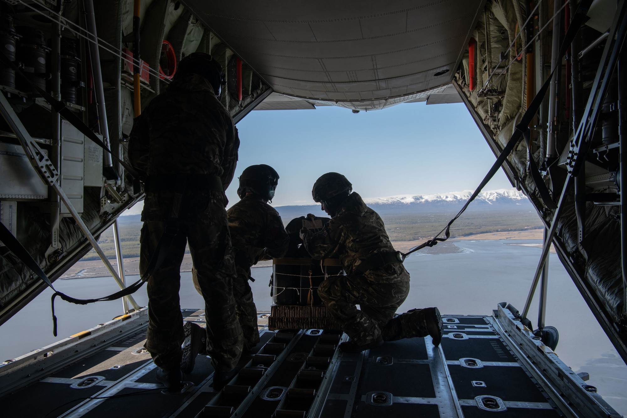 a photo of men throwing a package out of an airplane