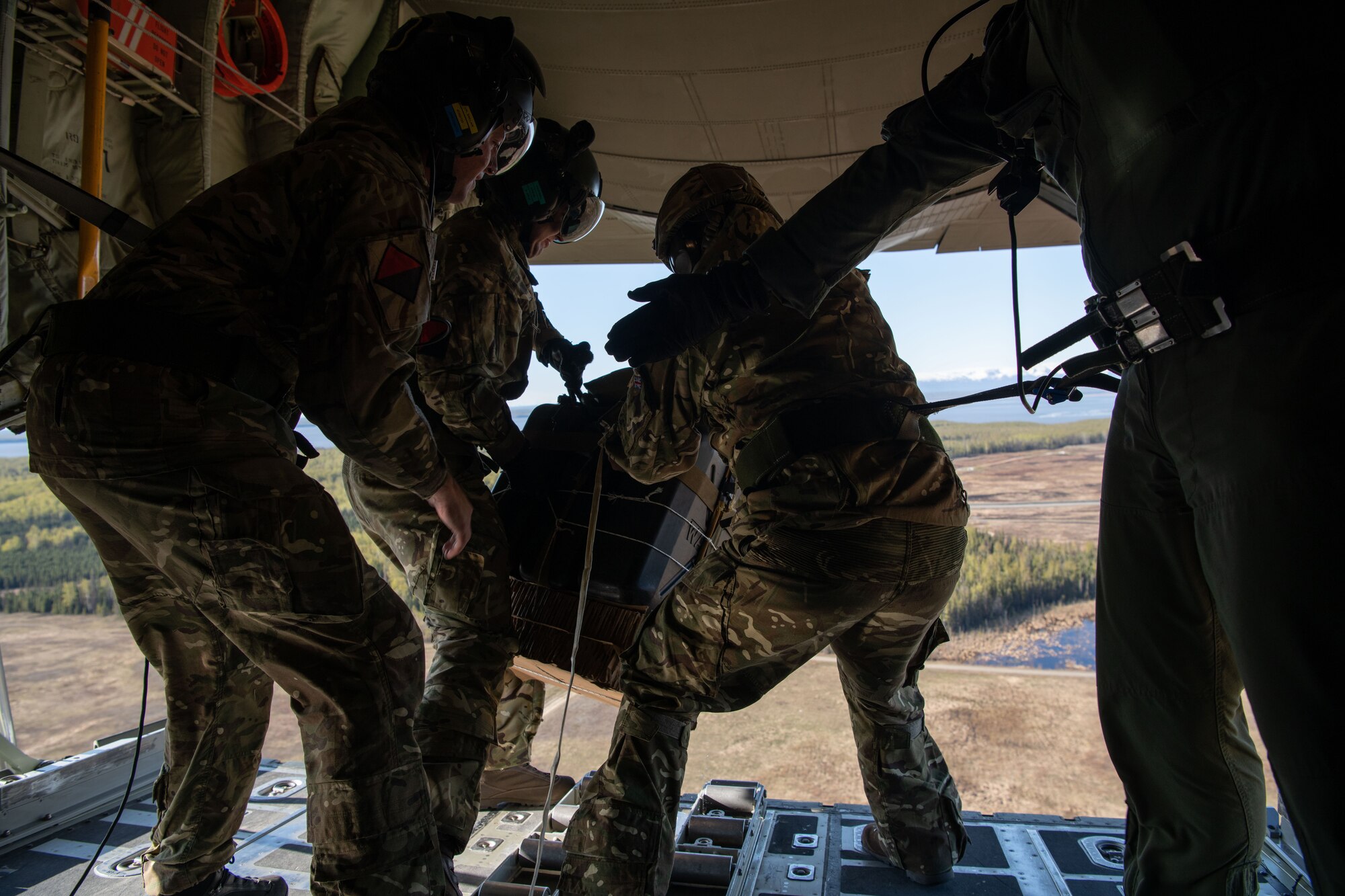 A photo of men throwing a package out of an aircraft