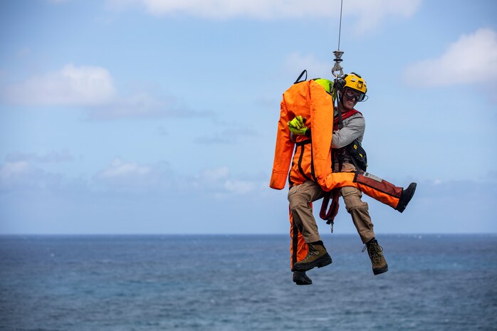 U.S. Coast Guard Aviation Survival Technician 2 Christopher Lynch, a rescue swimmer with Coast Guard Air Station Barbers Point, conducts a simulated vertical surface rescue at Pyramid Rock Beach, Marine Corps Base Hawaii, May 10, 2022. The Coast Guardsmen conducted vertical rescue training in order to evaluate the hazards, feasibility and techniques for recovering a survivor from a vertical surface. (U.S. Marine Corps photo by Cpl. Israel Ballaro)