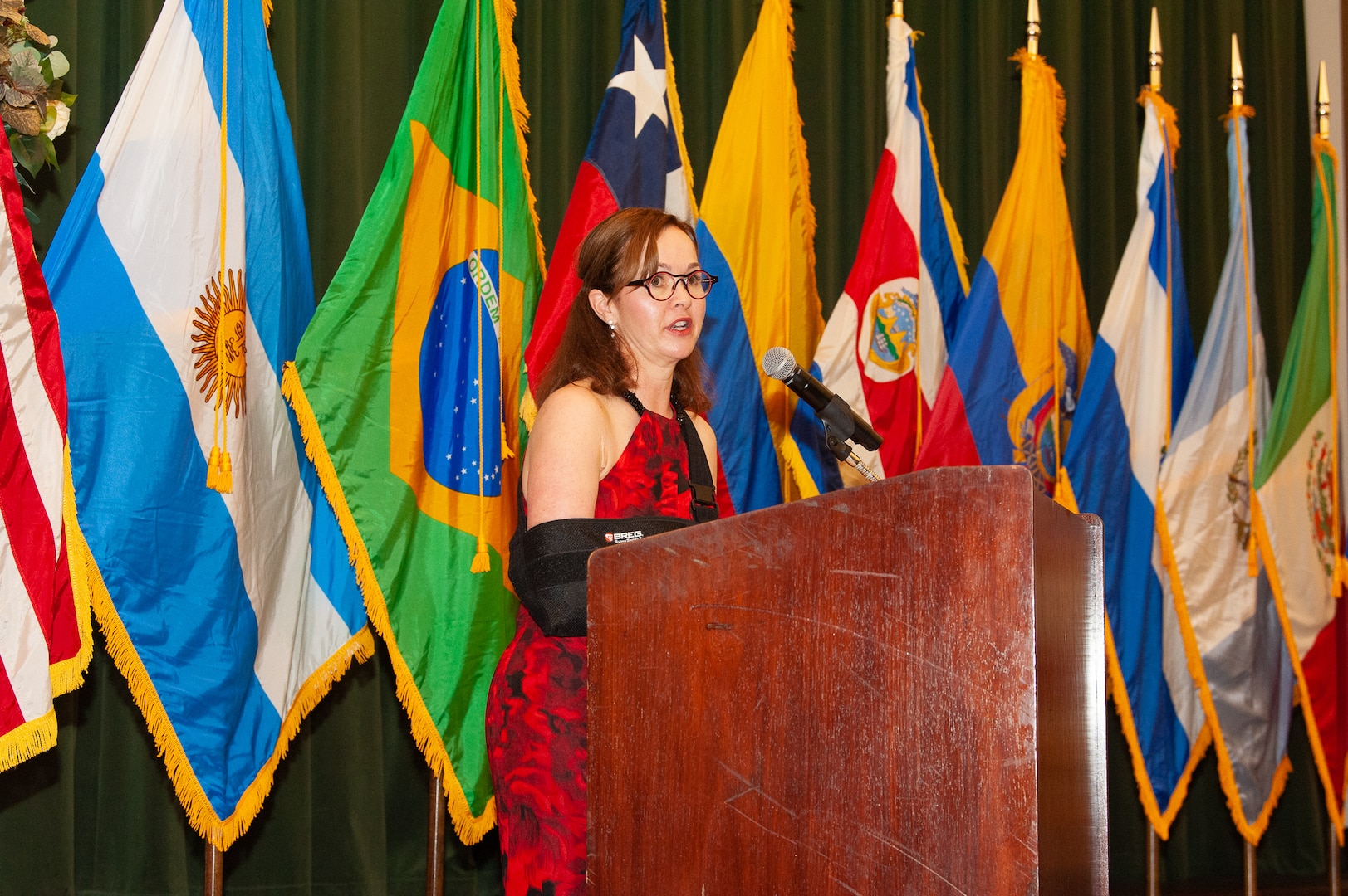 Kelli Seybolt stands at podium, with flags in background