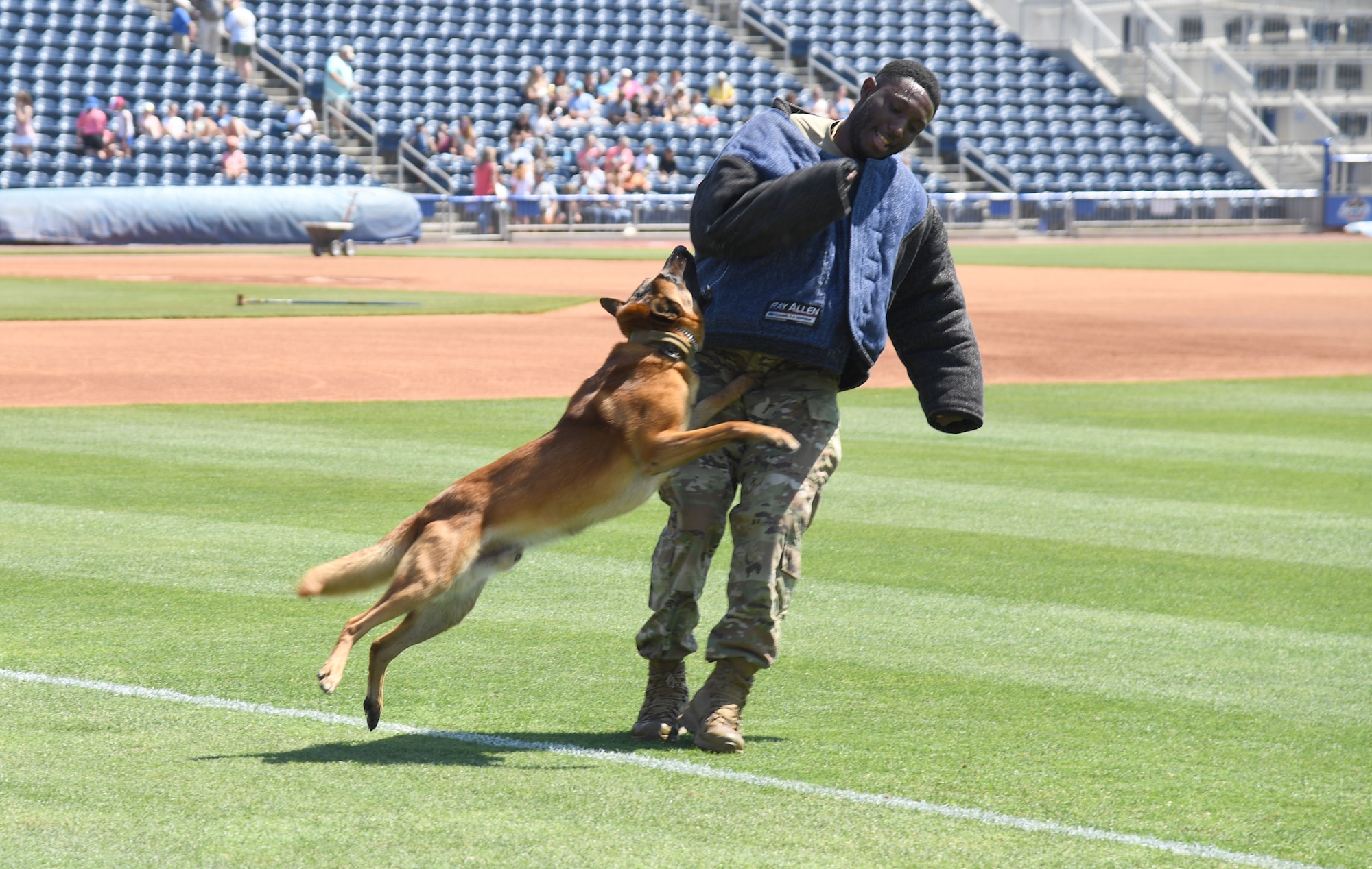 U.S. Air Force Senior Airman Victor Henderson, 81st Security Forces Squadron military working dog handler, and Victor, 81st SFS military working dog, participate in a military working dog demonstration during the Biloxi Shuckers Education Day event in Biloxi, Mississippi, May 11, 2022. The event allowed Airmen from the 81st Training Group to set up training equipment displays for local school-aged children to view during the Biloxi Shuckers' game. (U.S. Air Force photo by Kemberly Groue)