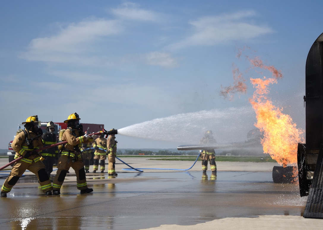 Two firefighters use a hose to spray water onto a fire.