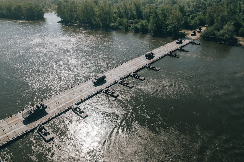 A float ribbon bridge system from the Army Prepositioned Stocks-2 worksite in Zutendaal, Belgium, is used by U.S., Polish, French and Swedish military forces to cross the Vistula River between Ryki and Kozienice, Poland, during DEFENDER-Europe 22, May 13. The float bridge is part of the 405th Army Field Support Brigade’s APS-2 program. This was the first time a float bridge system from the Zutendaal APS-2 site was transported to Poland and used during a DEFENDER-Europe exercise. (Photo by Michał Czornij)