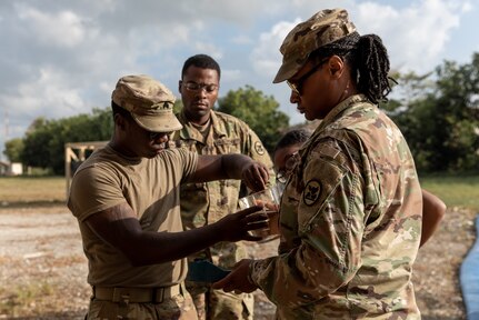 Alabama Army National Guard Sgts. Tymicheal Avery and Portia Staton test purified water during Operation Tradewinds 2022 at Price Barracks, Belize, May 13, 2022. Avery, Statonand the 1208th Quartermaster Company are supplying potable water for cooking, personal hygiene, and drinking to partner nations.