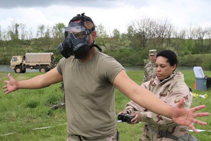 A New York National Guard Soldier with the 222nd Chemical Company, 104th Military Police Battalion performs a decontamination exercise at Fort Indiantown Gap on May 14. Another solider carefully removes the gas mask for gear decontaminating.